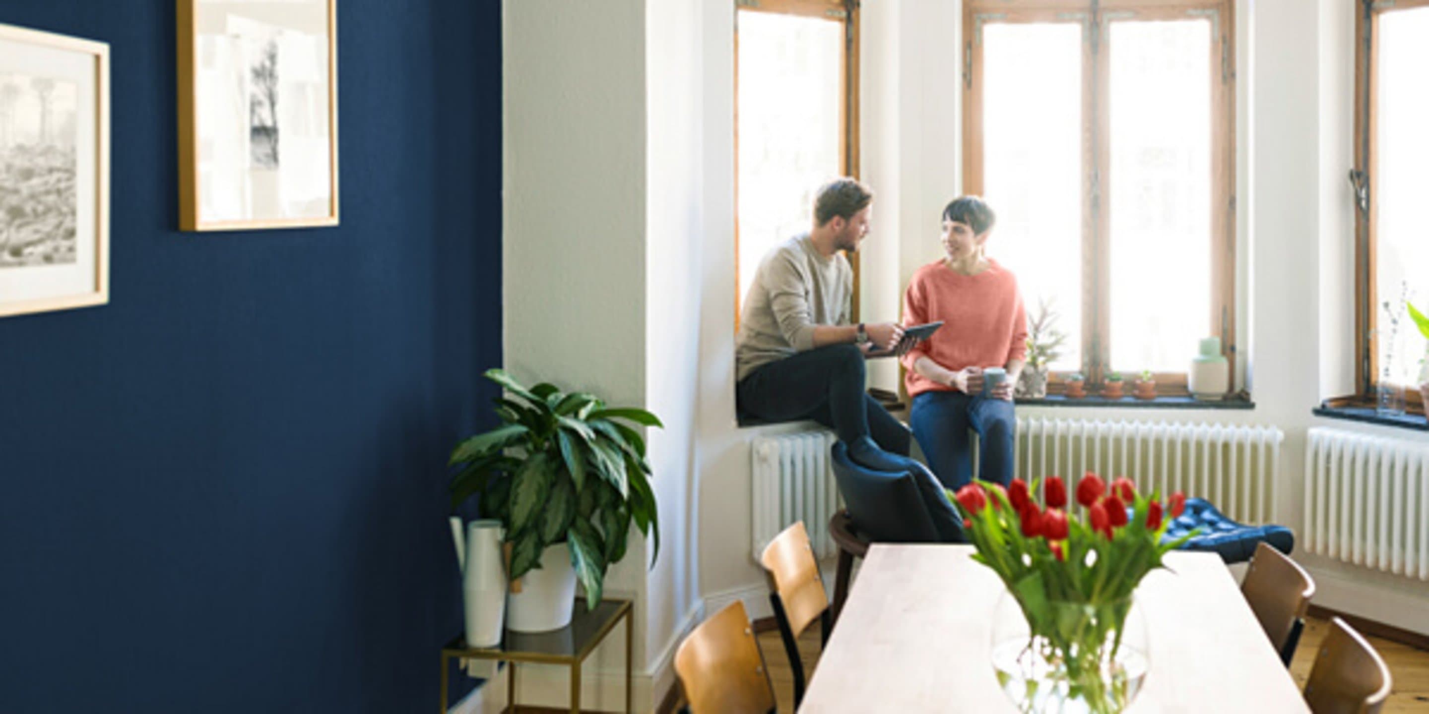 Paar hinter Küchentisch am Fenster unterhält sich.